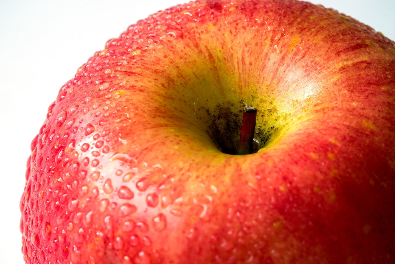 EXTREME CLOSE-UP OF APPLE ON RED BACKGROUND