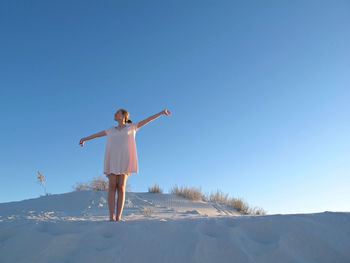 Low angle view of woman jumping against clear blue sky