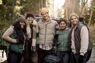 Portrait of smiling male and female friends standing together with arm around