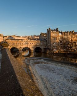 Arch bridge in city against clear sky