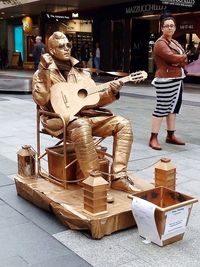 Statue of man sitting on sculpture in city