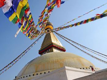 Low angle view of bodnath stupa decorated with prayer flags against clear sky