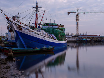 Fishing boats moored at harbor against sky