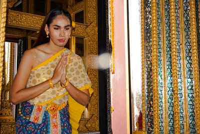 Beautiful young woman greeting while standing against wall