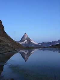 Scenic view of lake and mountains against clear blue sky