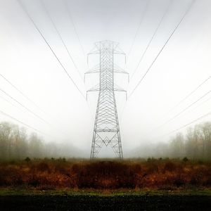 Electricity pylon on field in foggy weather