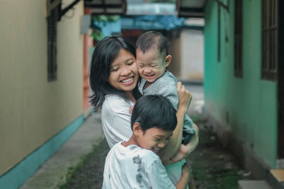 Smiling mother with sons standing outside house