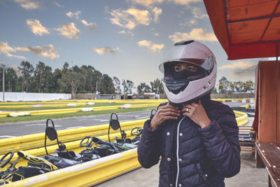 Portrait of adult woman holding helmet in go kart car.