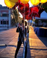 Woman looking away seen through balloons on footpath