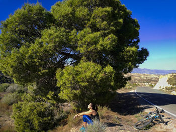 Woman sitting on field against sky