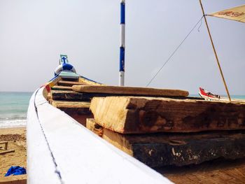 Close-up of boat moored at beach against sky