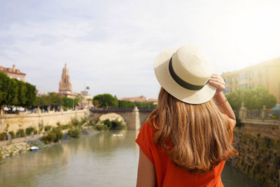 Tourist girl enjoying murcia cityscape with puente viejo bridge and cathedral bell tower, spain.