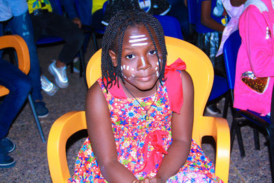 Portrait of girl with face paint sitting on chair