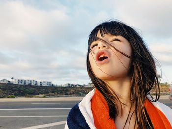 Close-up of girl standing against sky