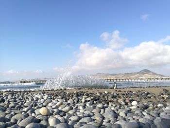 Pebbles on beach against blue sky