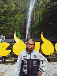 Portrait of man standing against waterfall