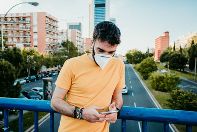 Man standing on railing in city