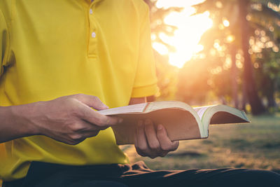 Midsection of man reading book