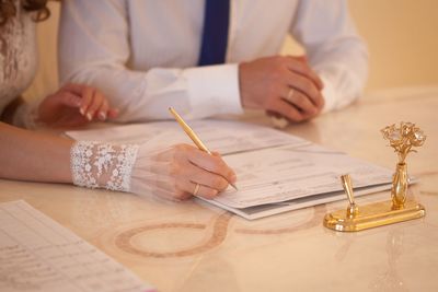 Midsection of bride signing document during wedding ceremony