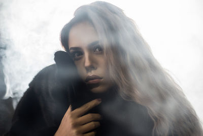 Close-up portrait of young woman against sky