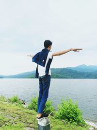 Rear view of man standing on mountain against sky