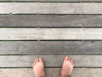 Low section of person standing on wooden floor