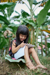 Full length of woman sitting against plants