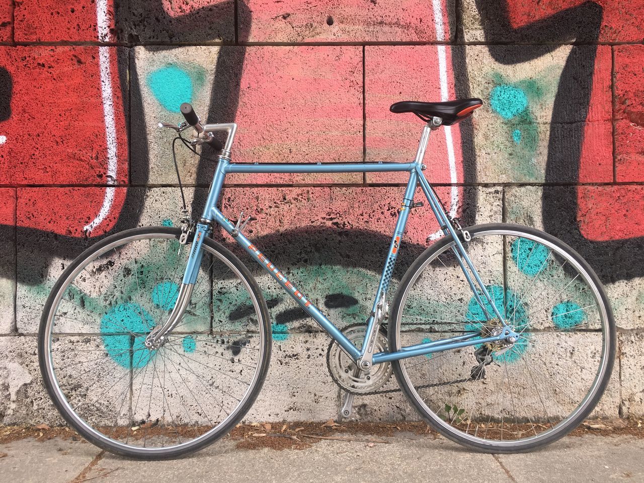 bicycle, land vehicle, transportation, stationary, mode of transportation, wall - building feature, wall, day, no people, architecture, built structure, graffiti, parking, building exterior, outdoors, leaning, basket, footpath, pink color, nature, wheel