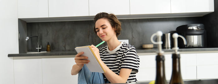 Young woman using mobile phone while sitting at home