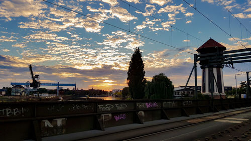 View of railroad bridge in city against sky during sunset