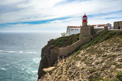 Lighthouse on beach against sky