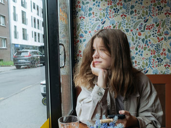 Portrait of a young girl sitting at the window of the cafe