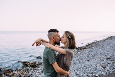 Stylish lovely couple walking and hugging by the sea enjoying time together