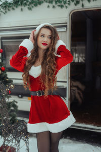 Portrait of young woman standing against christmas tree