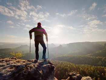 Rear view of man standing on mountain against sky