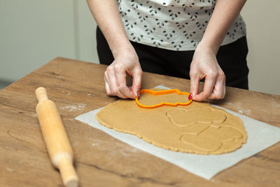 Midsection of woman using pastry cutter on dough