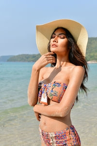 Sensuous young woman wearing bikini standing at beach
