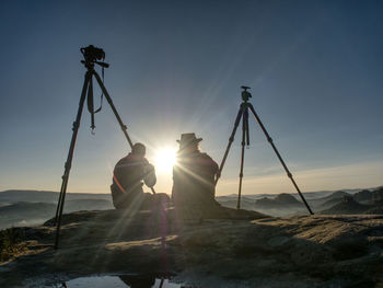 Creative artists stay at own cameras on tripods. photo enthusiasts work together on cliff