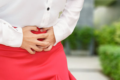 Midsection of woman with red standing against blurred background