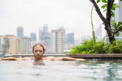 Portrait of shirtless man relaxing in swimming pool