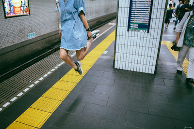 Low section of person walking on railroad station platform