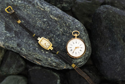 Close-up of pocket watch and wristwatch on rock