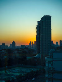 Modern buildings against sky during sunset