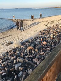 People on rocks by sea against sky