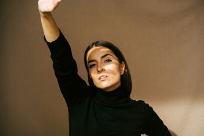 Portrait of young woman standing against wall