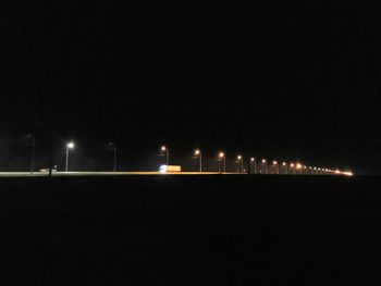 Illuminated street lights against clear sky at night
