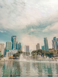 Water fountain in swimming pool against buildings in city