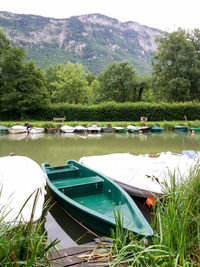 Boats moored by lake against sky