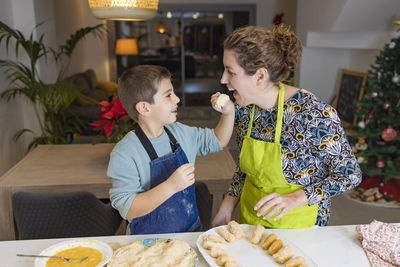 Son feeding food to mother at home