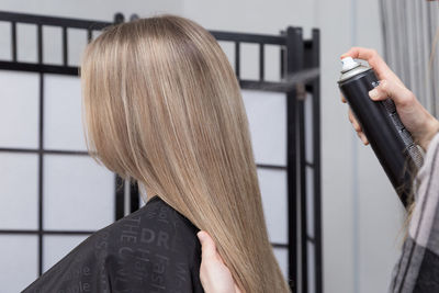 Cropped hand of hairdresser holding woman hair at salon